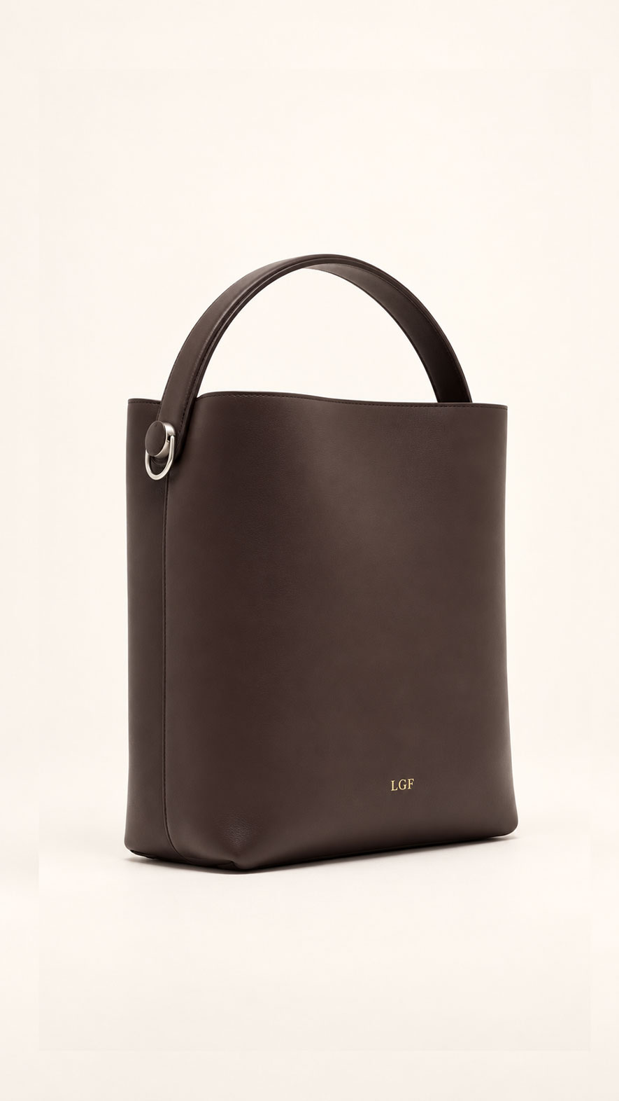 Angled view of espresso leather bucket tote with top handle and gold LGF logo