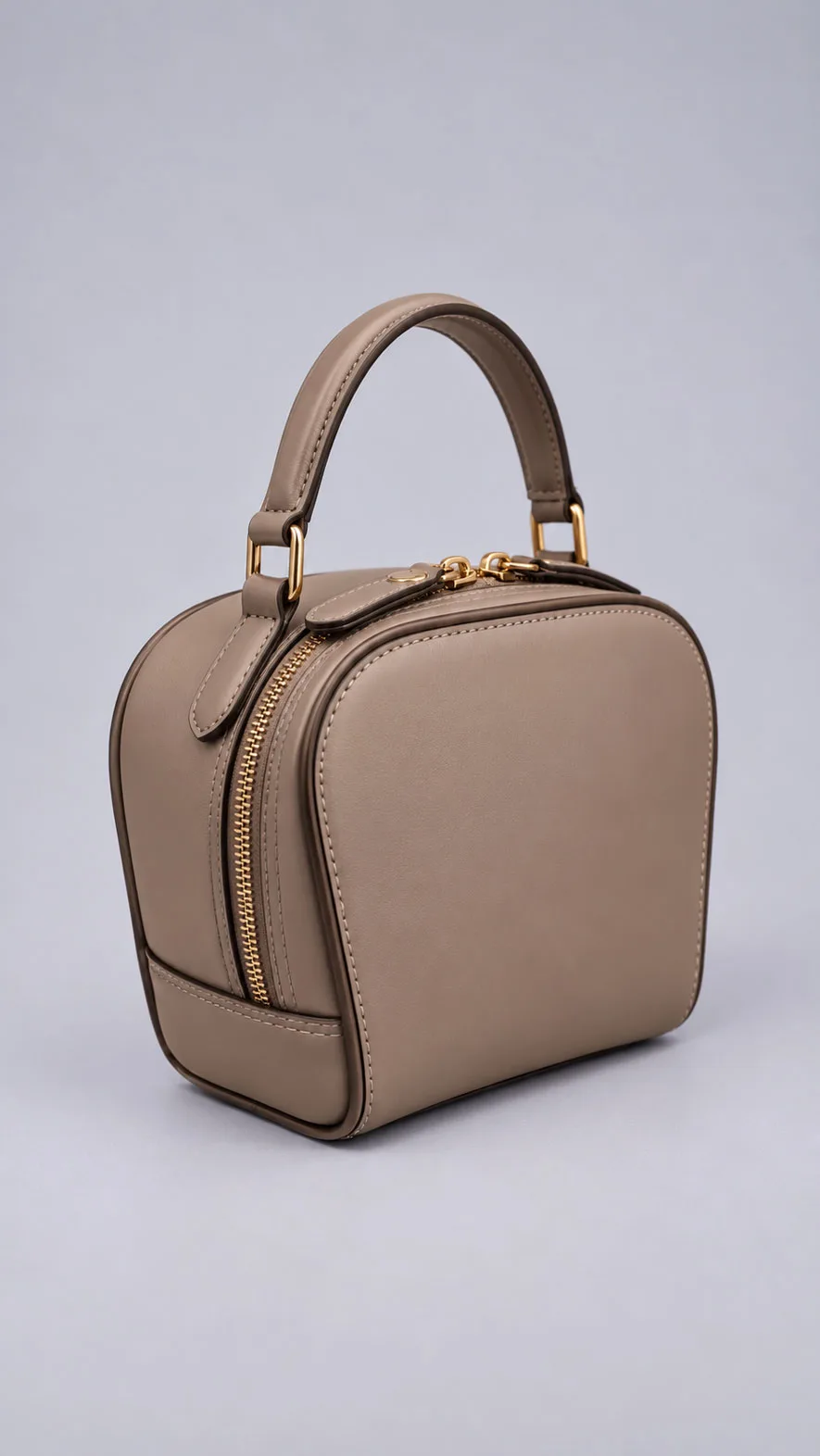 HB0443 taupe dome leather handbag showing double zipper and dark edge piping, angled view